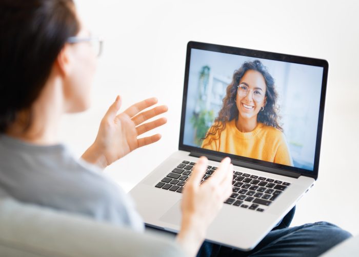 woman is using laptop for remote conversation Young woman is using laptop for remote conversation with friend. People having fun staying at home.
